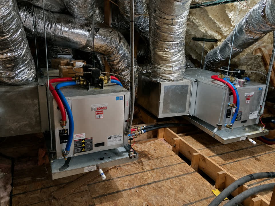 Two Bosch geothermal heat pumps installed side by side in a spray-foamed DFW attic with insulated ductwork