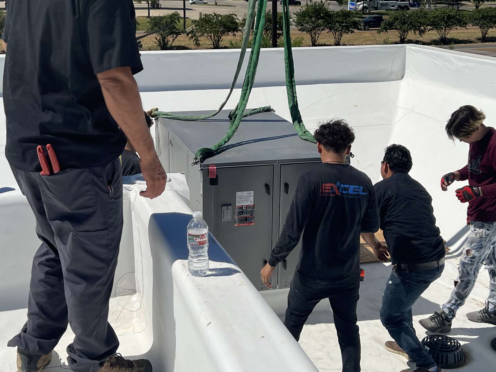 Excel team setting a craned heat-pump unit on the roof at Home2 Suites