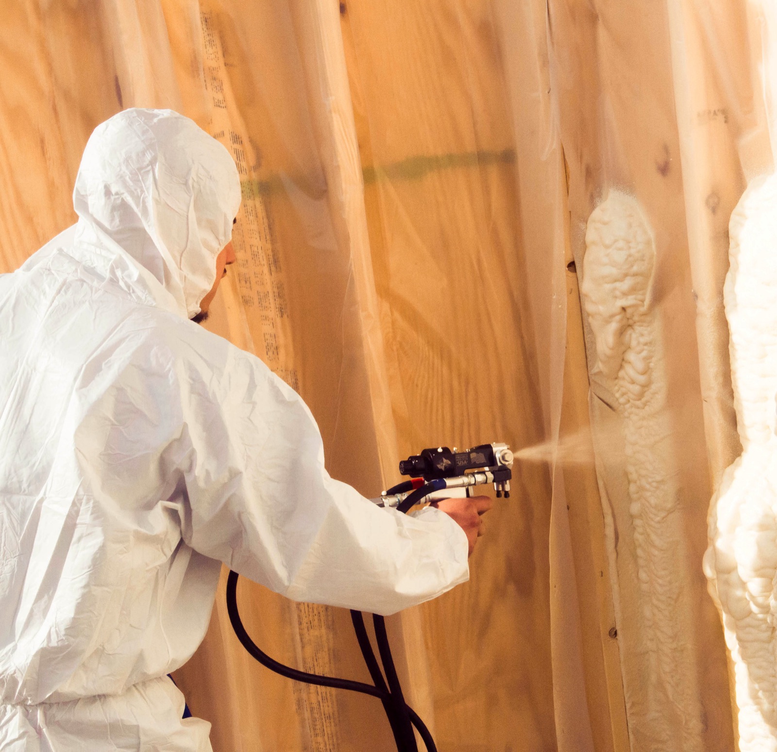 Excel Geothermal technician in protective gear applying spray foam insulation